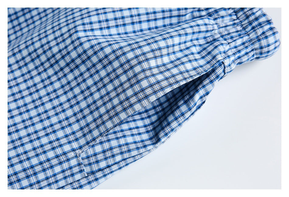 Close-up of blue-and-white plaid garment fabric with gathered stitching and a folded seam.