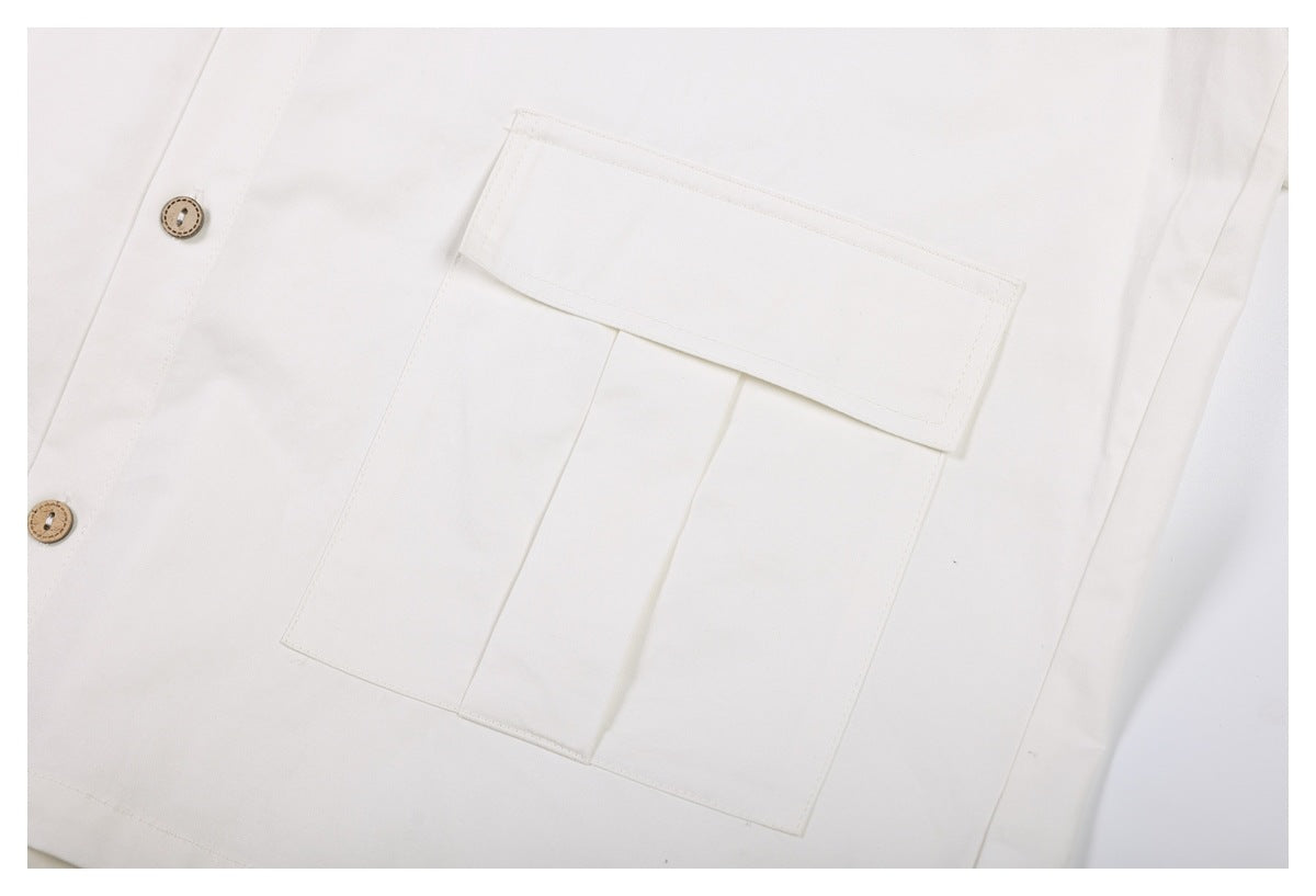 Close-up of a white garment's large flap pocket with stitched seams and tan buttons.