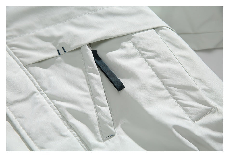 Close-up of a white jacket pocket flap and dark zipper pull.