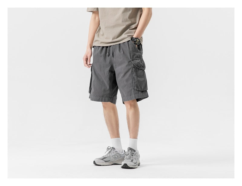 Three-quarter front view of a model in charcoal gray cargo shorts with a drawstring waist and flap pockets.