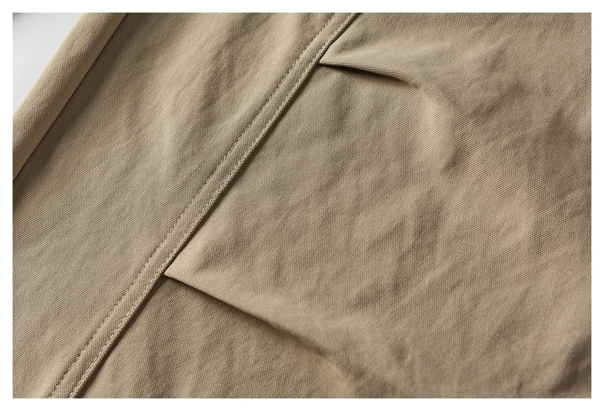 Close-up of tan trousers showing a stitched seam and flap pocket.