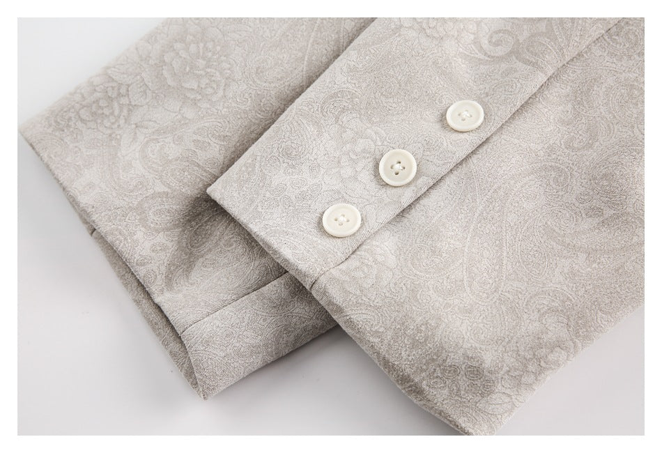 Close-up of a light taupe paisley garment cuff with three white buttons.