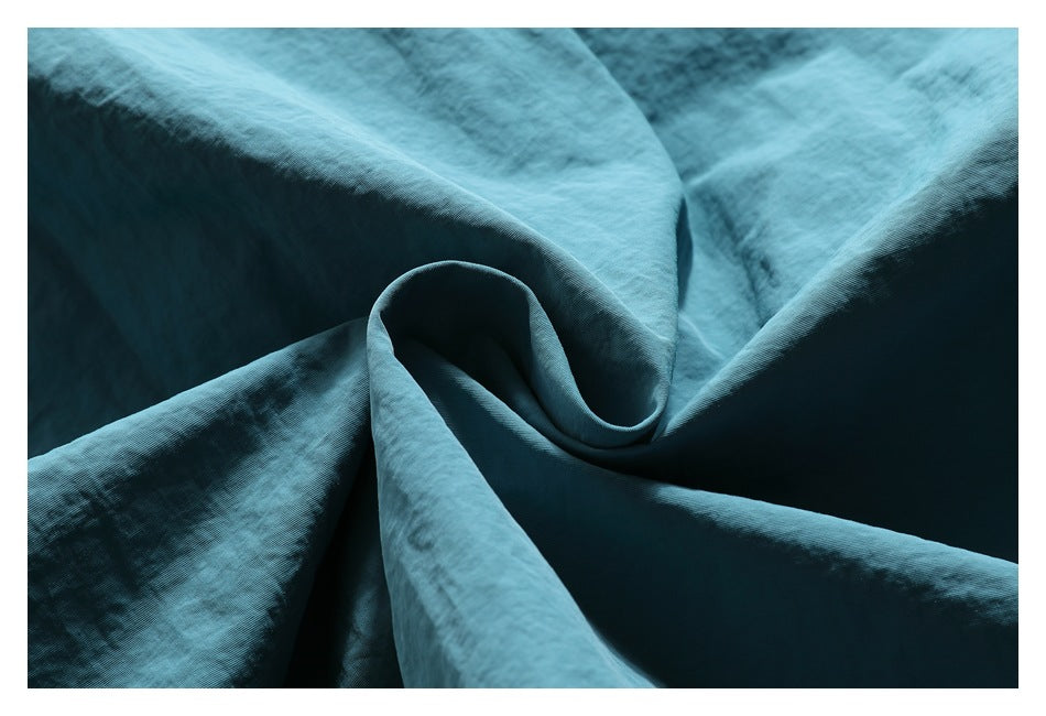 Macro view of the teal garment fabric draped into soft folds.