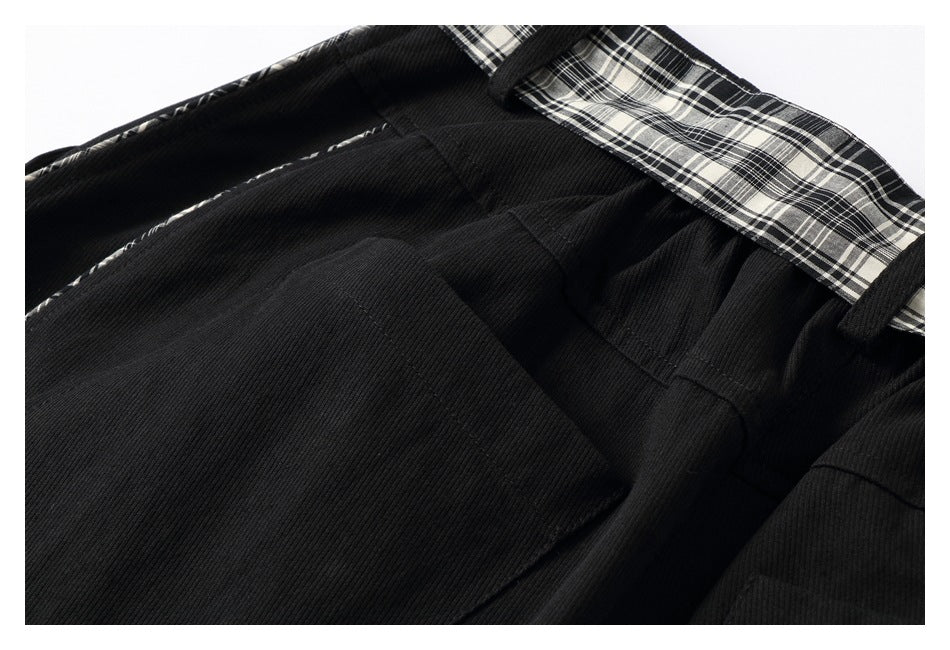 Close-up of black trousers showing a front pocket, waistband, belt loop, and plaid lining.