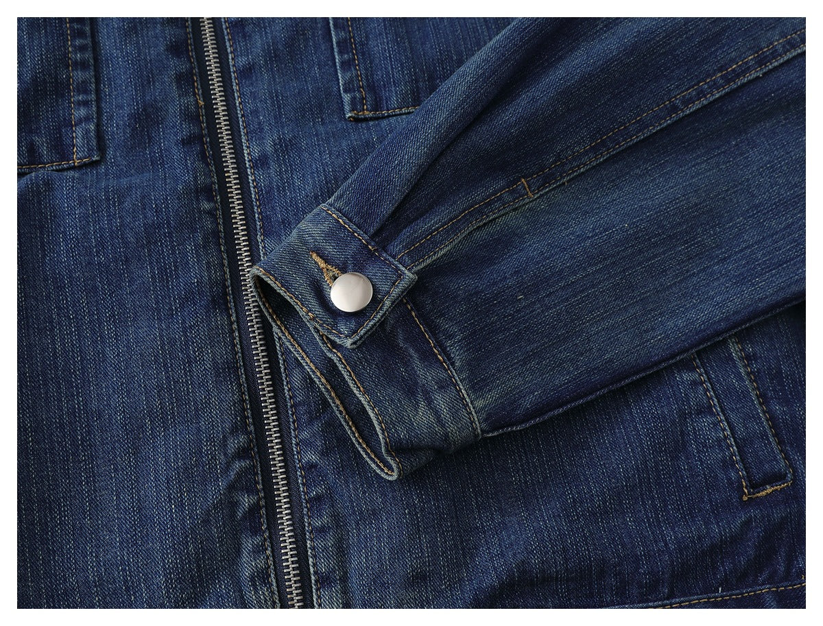 Close-up of a denim jacket sleeve cuff with a silver snap button beside the front zipper.