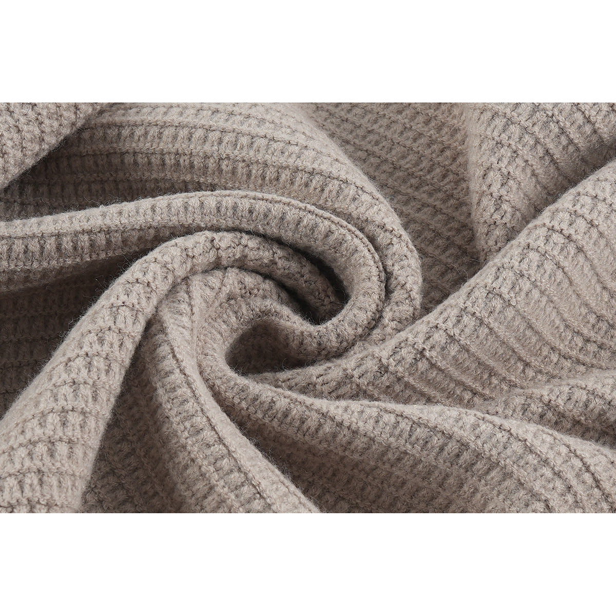 Close-up of taupe knit fabric arranged in folds, showing its raised textured stitch pattern.