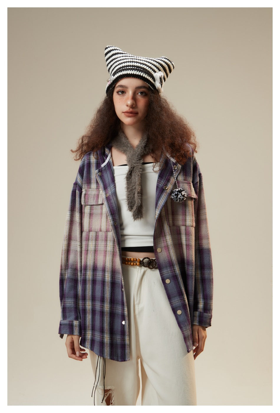 Model wearing an open purple plaid jacket with snap buttons and chest pockets over a white top, with a striped knit hat.