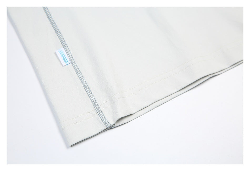 Close-up of an off-white garment hem with parallel stitching and an overlocked side seam.