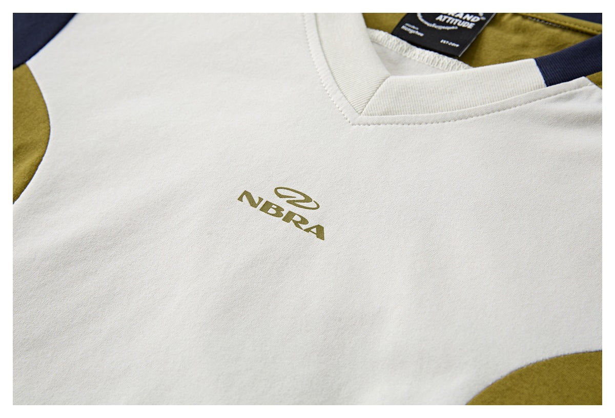 Close-up of an ivory T-shirt chest with an olive logo and navy and olive color-block accents.