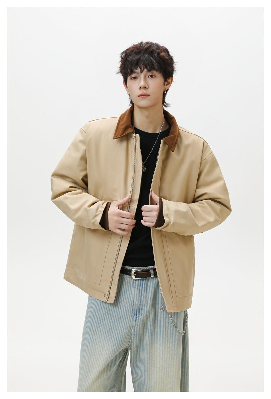 Model wearing an open beige jacket with a brown collar over a black shirt; front zipper and patch pockets are visible.