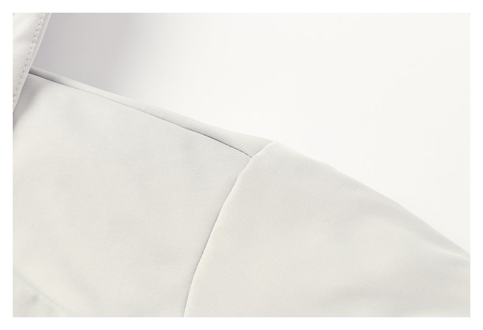 Close-up of a pale gray jacket shoulder showing its stitched seam and panel construction.