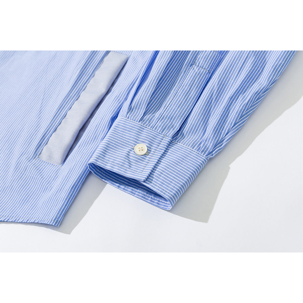 Close-up of a blue-and-white striped shirt sleeve and buttoned cuff beside a solid blue panel.