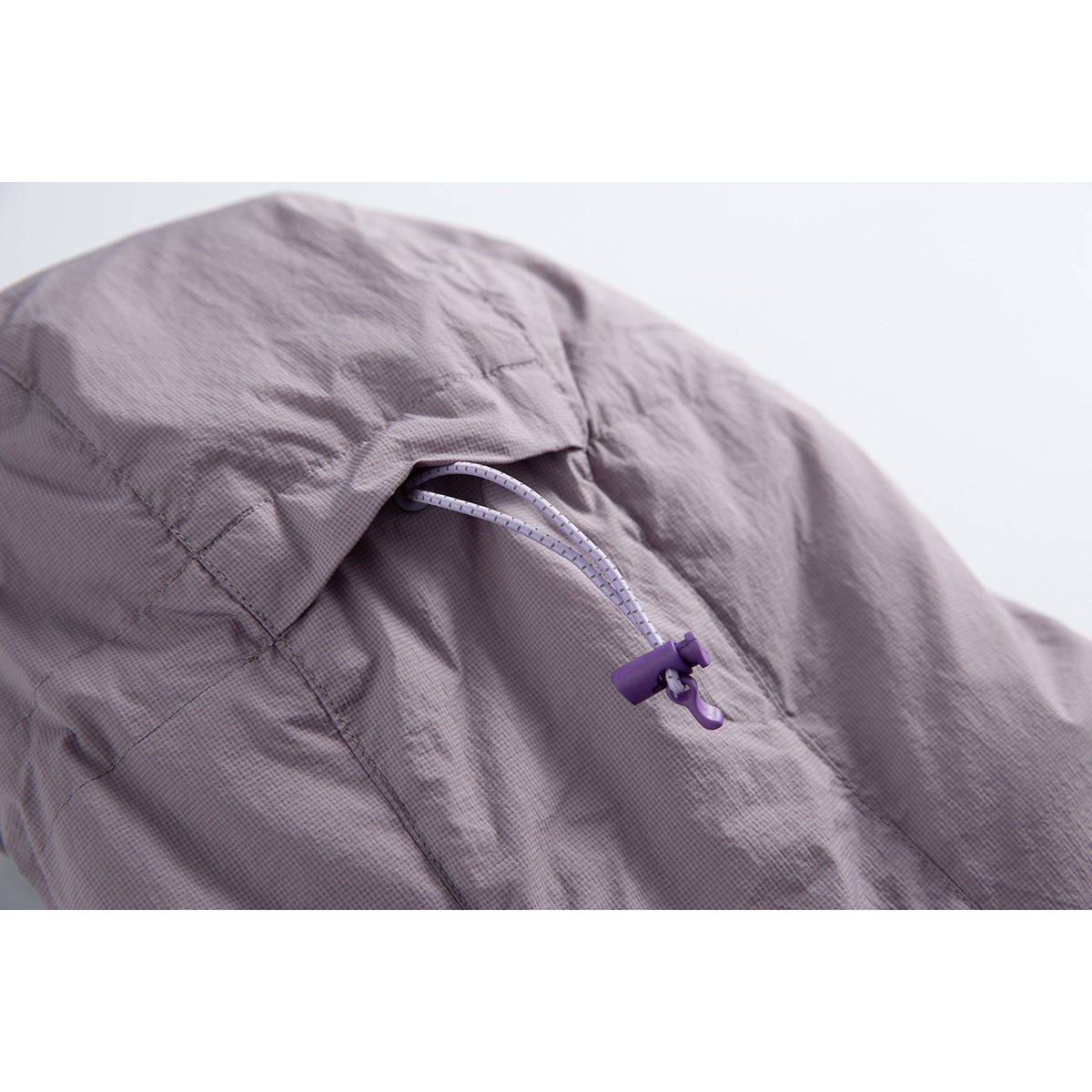 Close-up of a lavender-gray jacket hood with a purple cord lock and adjustable drawcord.