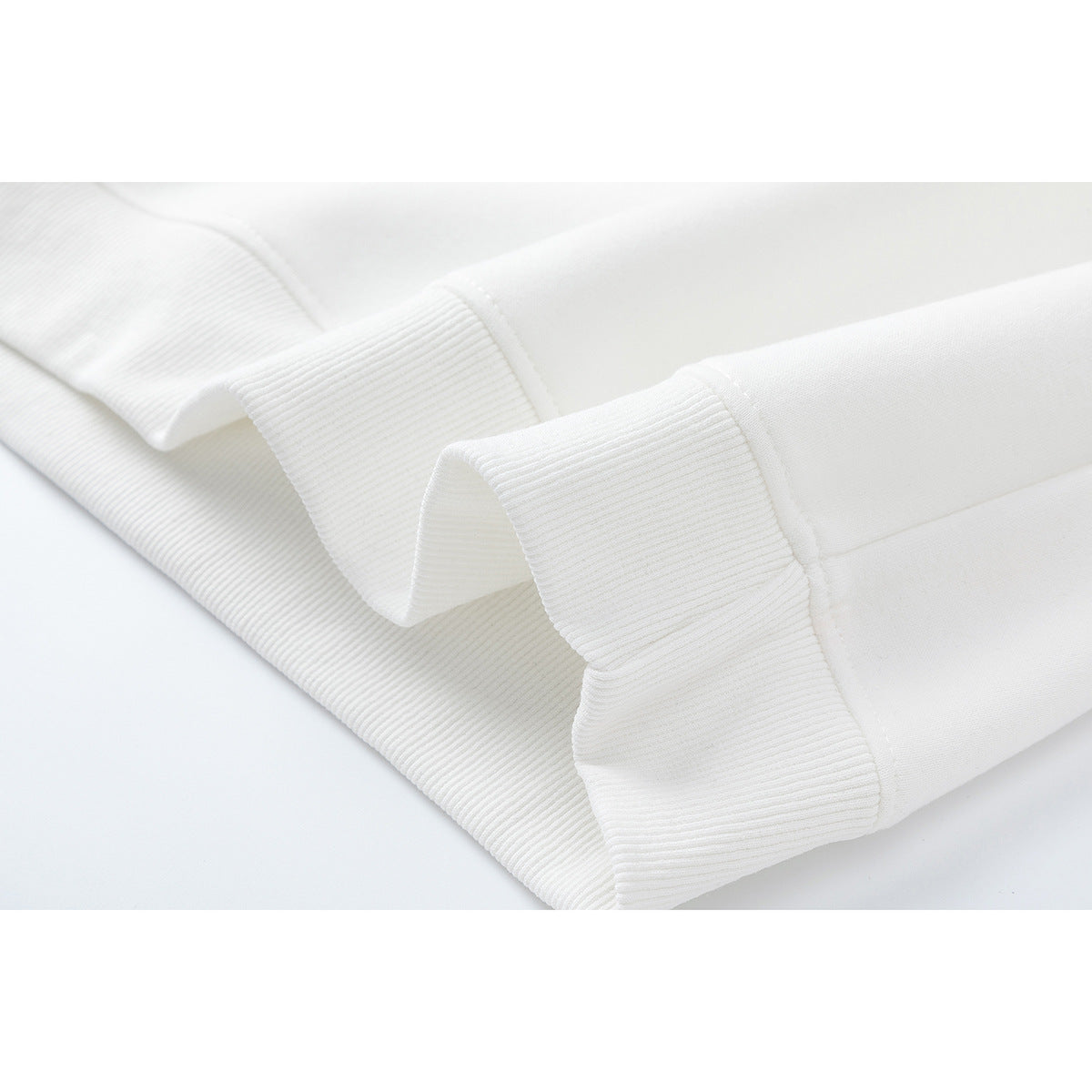 Close-up of the white sweatshirt's ribbed cuffs and hem.