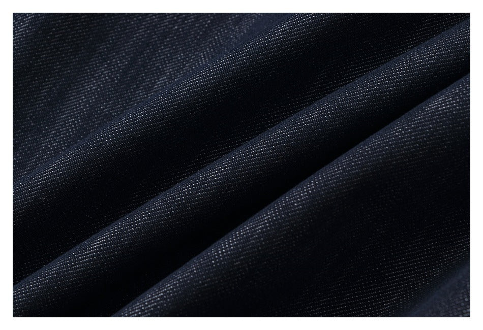 Macro view of dark indigo fabric folded into soft ridges, showing its fine diagonal weave.