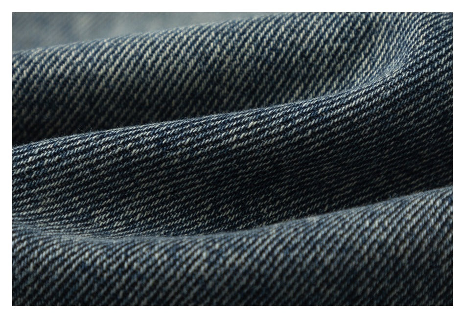 Close-up of dark blue fabric with a diagonal twill weave and overlapping folds.