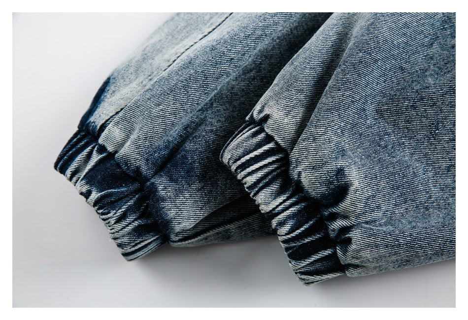 Close-up of gathered elastic cuffs on faded blue denim pants.