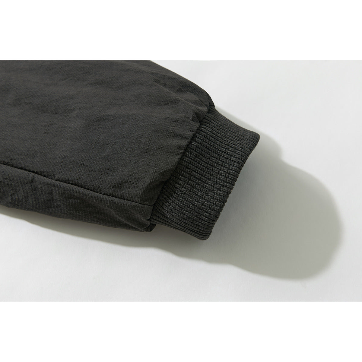 Close-up of the dark jacket's sleeve and ribbed knit cuff.