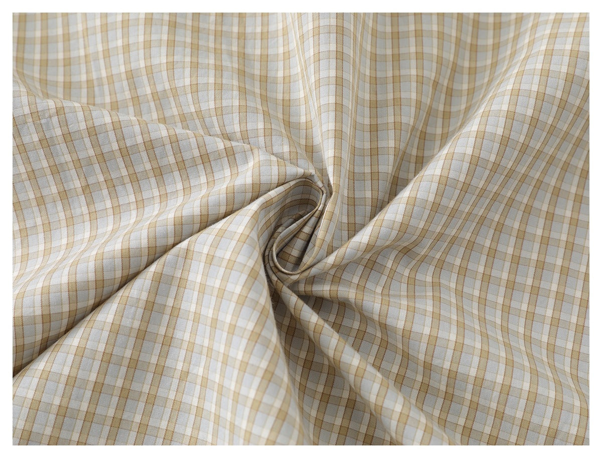 Beige, white, and muted brown plaid shirt fabric gathered to show its pattern and drape.