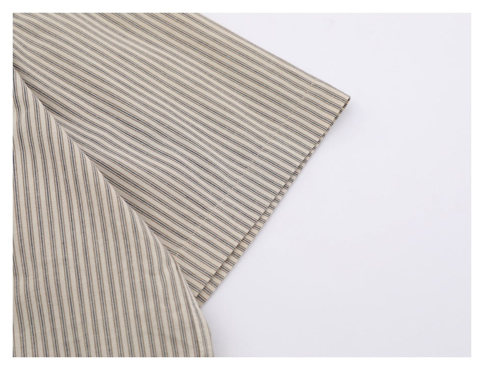 Close-up of a beige shirt sleeve with narrow brown and gray stripes and a finished edge.