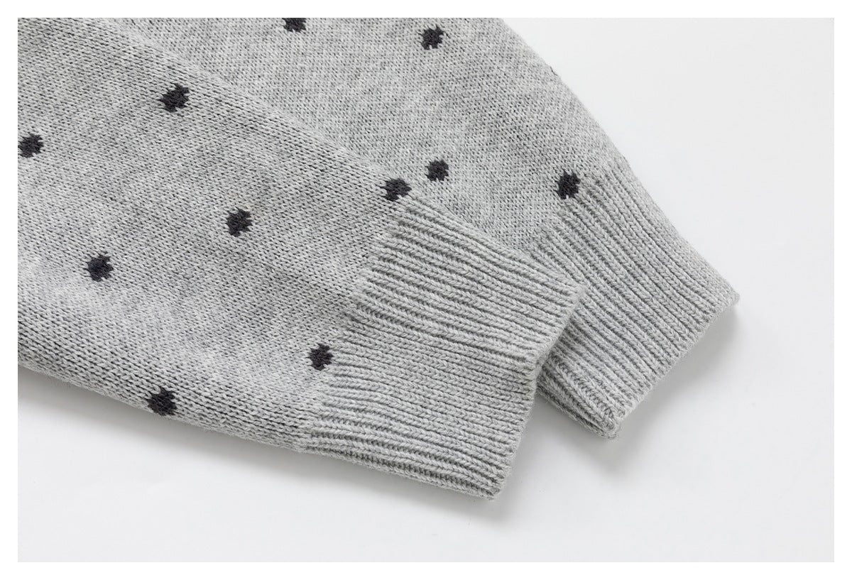 Close-up of a ribbed cuff on a light gray knit sleeve with small charcoal dots.