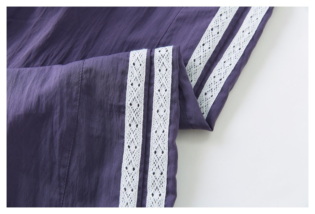Close-up of purple pants showing twin white lace side stripes and stitched panel seams.