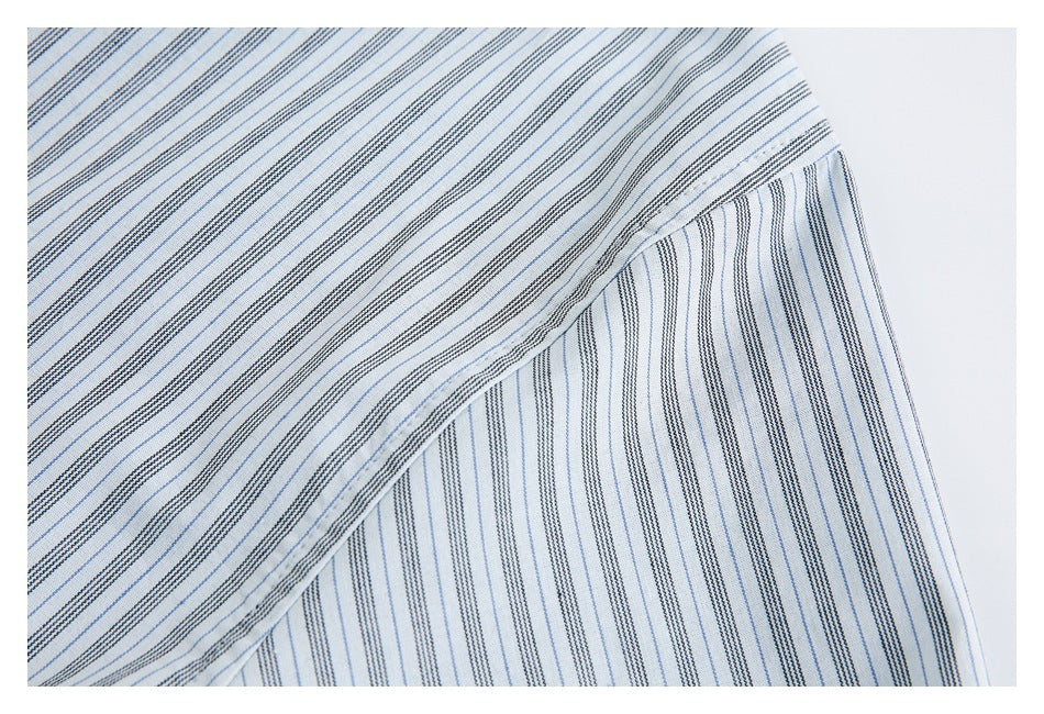 Close-up of white fabric with narrow blue and black stripes, folded to show a stitched edge.