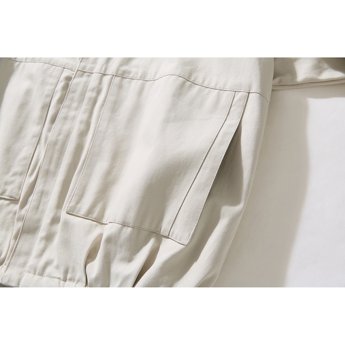 Close-up of the ivory jacket's large rectangular front patch pocket and seam details.