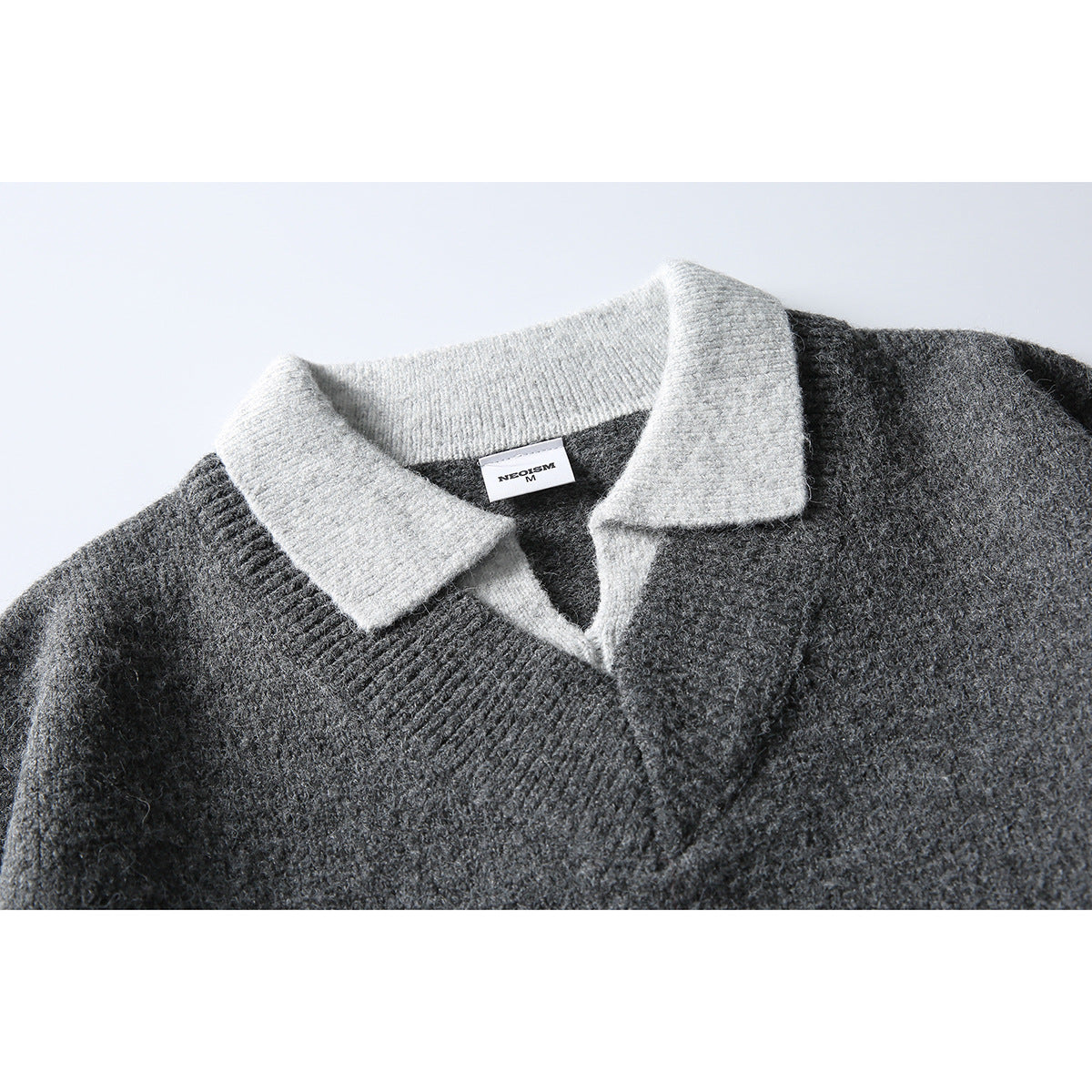 Close-up of a charcoal knit sweater with a contrasting light gray ribbed collar and V-neck opening.