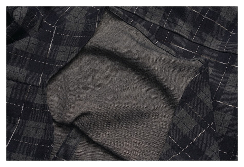 Close-up of a dark gray plaid garment opened to show its plain gray lining.