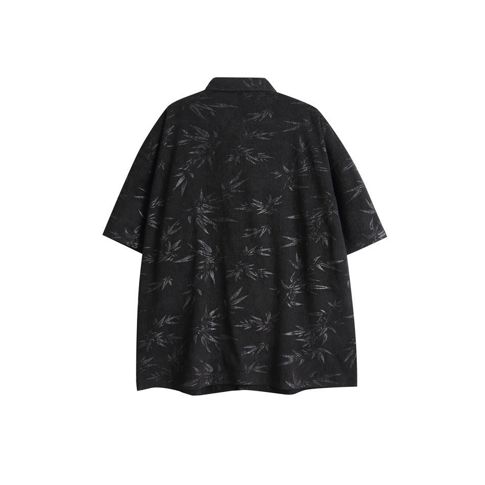 Flat-lay back view of a black short-sleeve tunic with a subtle all-over leaf pattern.