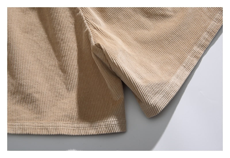 Close-up of the leg openings and stitched hems on tan corduroy shorts.