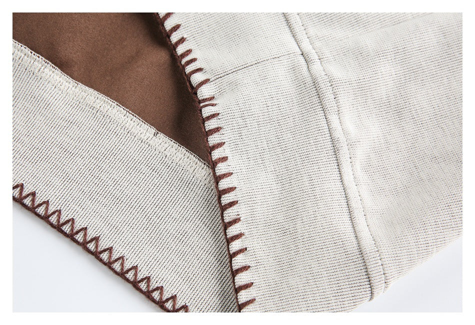 Close-up of the cream garment's opening and seam, finished with brown blanket stitching.