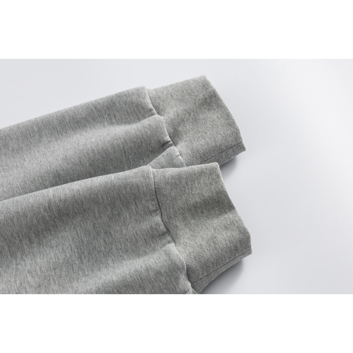 Close-up of two heather gray pullover sleeves with ribbed cuffs.