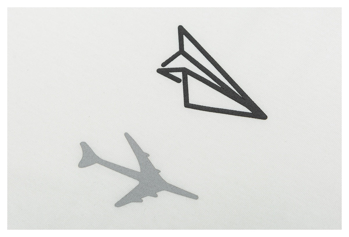 Close-up of a black paper airplane graphic printed on white fabric.