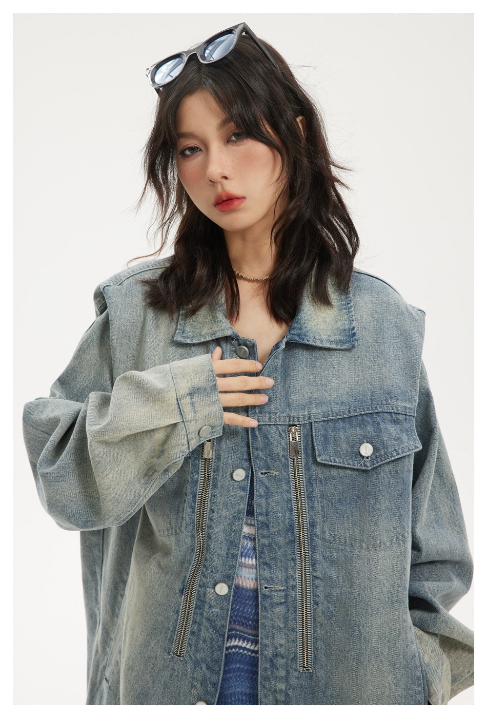 Close-up of the faded blue denim jacket's wide collar, flap pocket, metal buttons, and long front zippers.