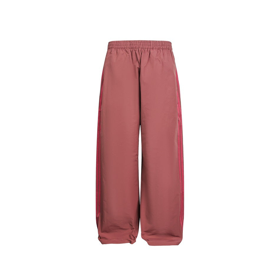 Rose-pink wide-leg track pants with elastic waist and deeper pink side stripes, flat front view