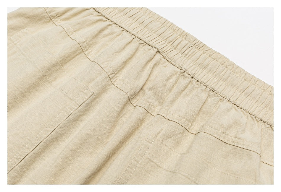 Close-up of the back of beige bottoms with an elastic waistband and stitched patch pockets.