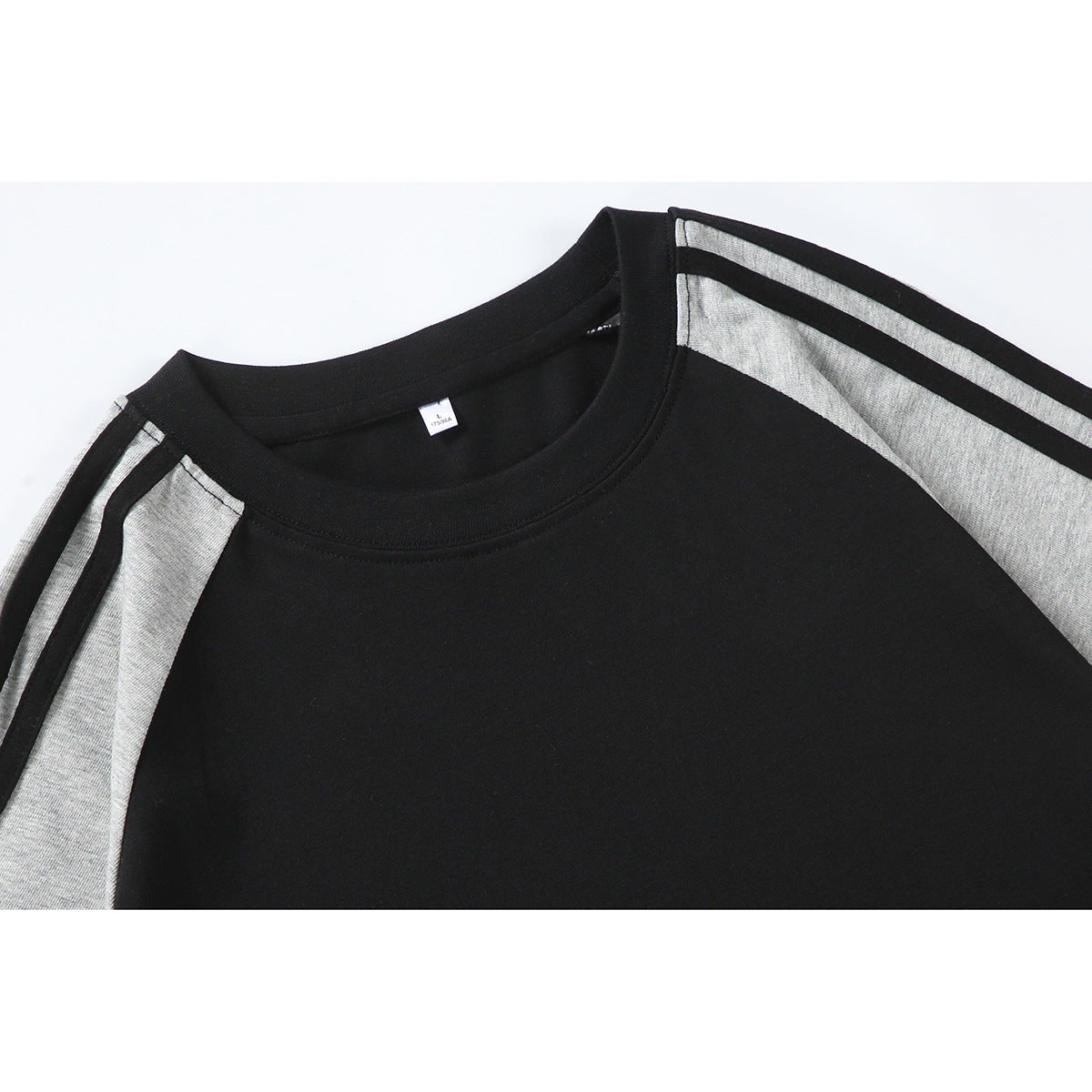 Close-up of a black crew-neck T-shirt with gray raglan panels and narrow shoulder stripes.