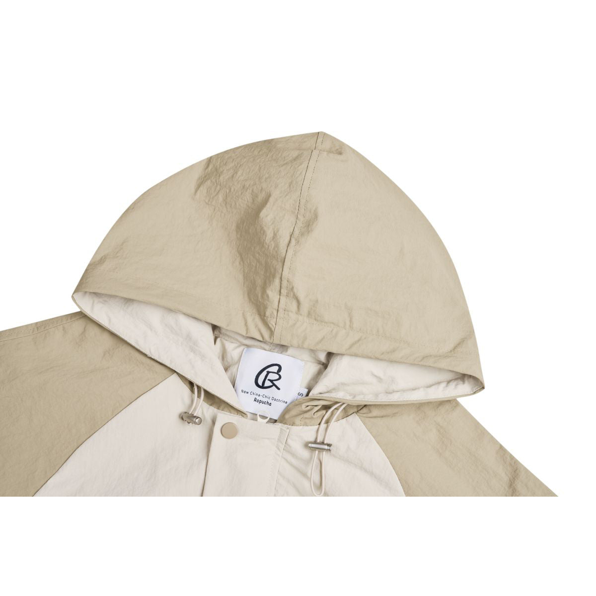 Close-up of a beige hood, drawcords and inner neck label on a pullover jacket.