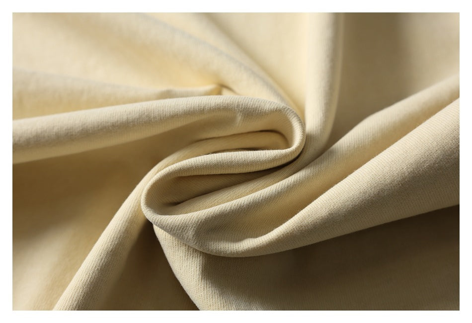 Close-up of pale cream fabric gathered into soft folds, showing its knit texture.