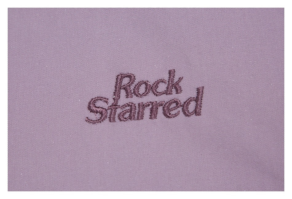 Close-up of the words “Rock Starred” embroidered on mauve fabric.