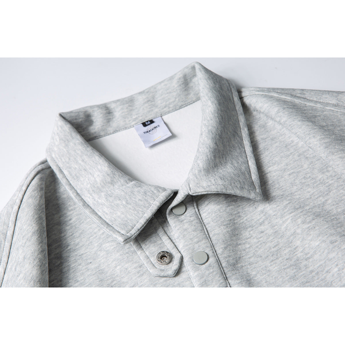 Close-up of a light heather-gray polo shirt collar and snap-button placket.