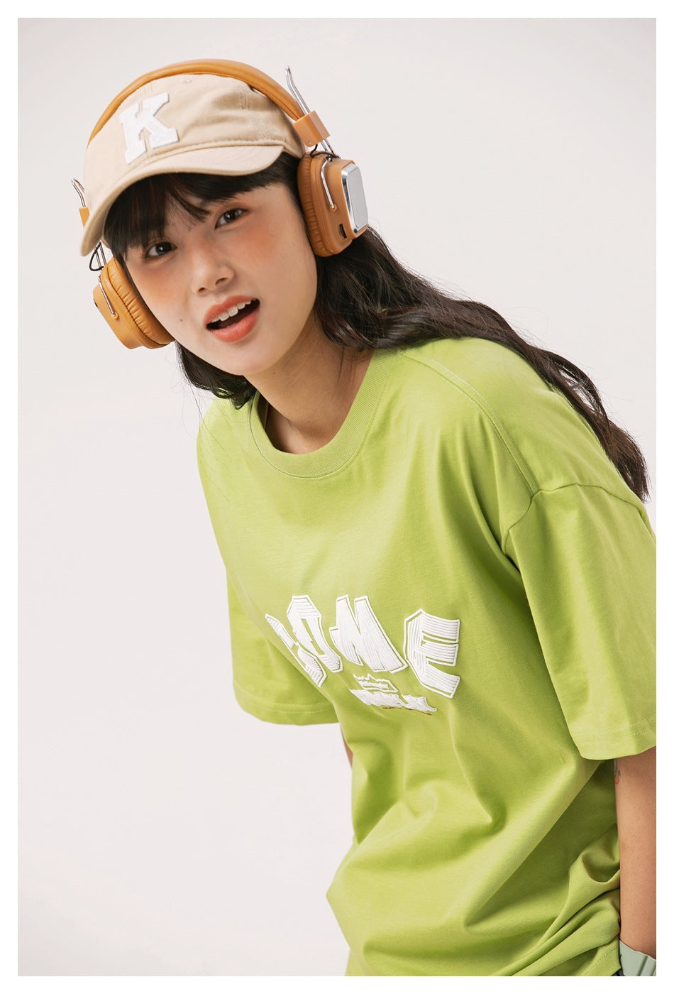 Angled close-up of a model wearing a lime green oversized T-shirt with a partially visible white chest graphic.