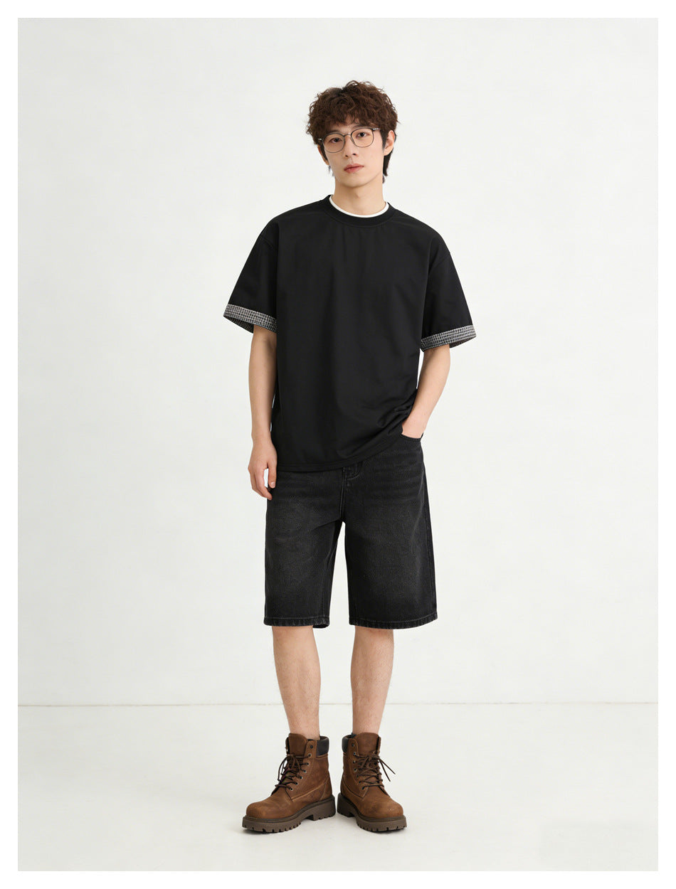 Model standing in a black tee with plaid cuffs, black denim shorts and brown lace-up boots