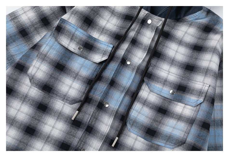 Close-up of the plaid overshirt front showing two snap-button chest pockets, front snaps and hood drawstrings.