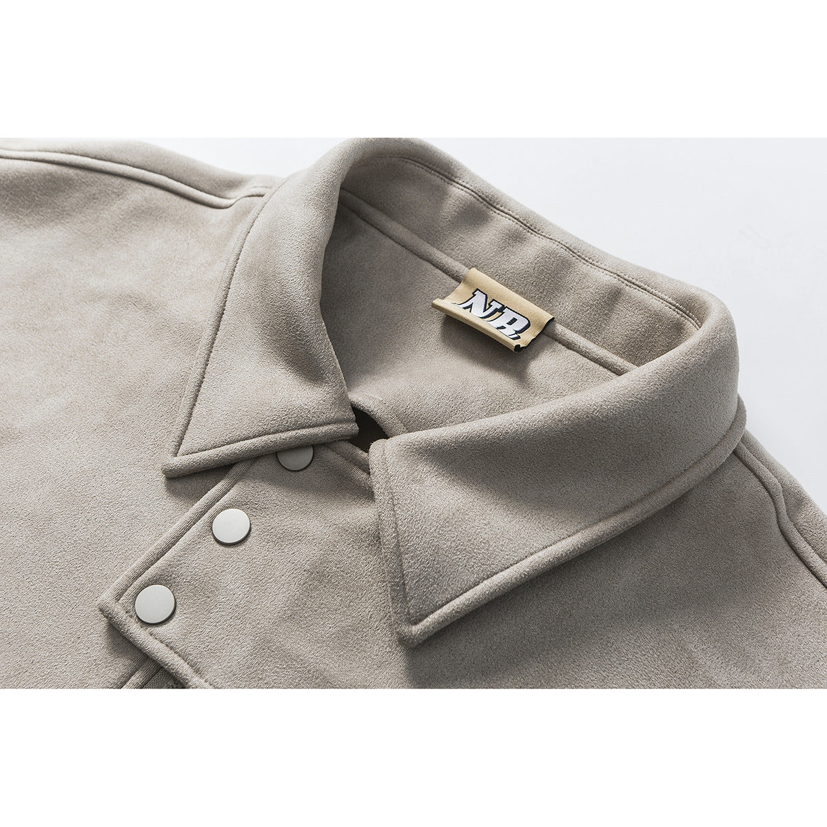 Close-up of a taupe jacket collar, inner label, and round front snaps.