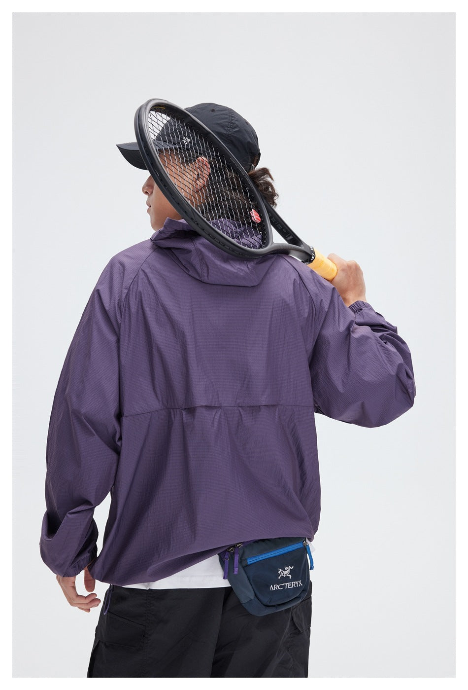 Back view of a person wearing a purple hooded jacket, with a small blue pouch at the waist.