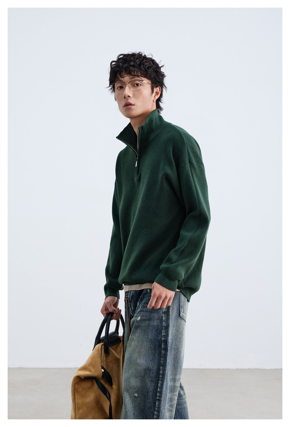 Model in a dark green quarter-zip pullover and jeans, shown from a close front three-quarter angle.