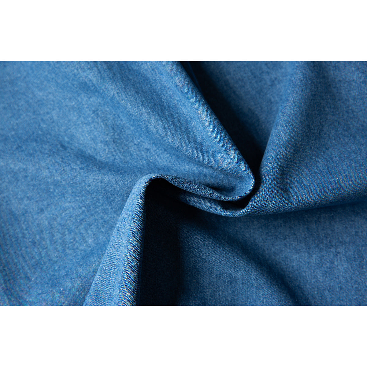 Macro view of blue denim fabric arranged in soft folds.